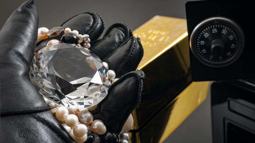 Home invasion and burglary concept with hand in leather gloves holding the loot a diamond and pearl necklace