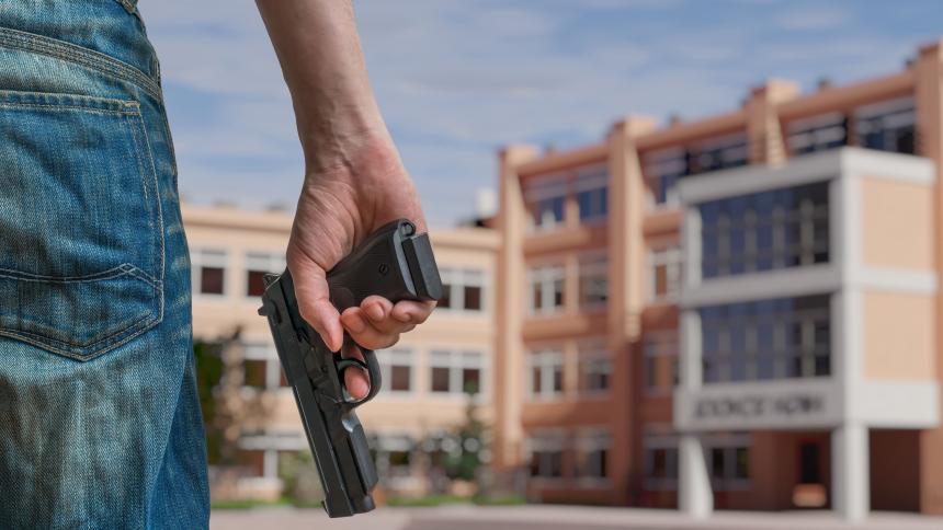 A man holding a gun outside of a high school