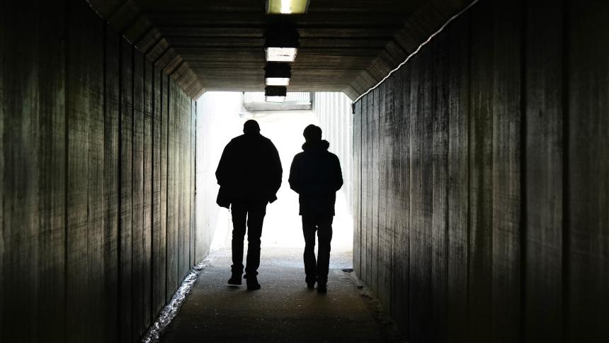 two people walk to the light at the end of a tunnel