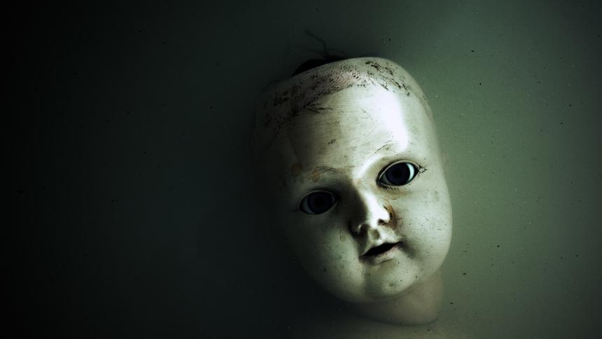 Creepy doll face in dark dirty water