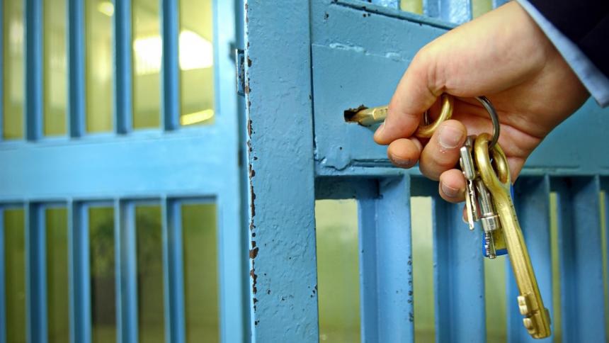 A prison guard using keys to lock a prison cell