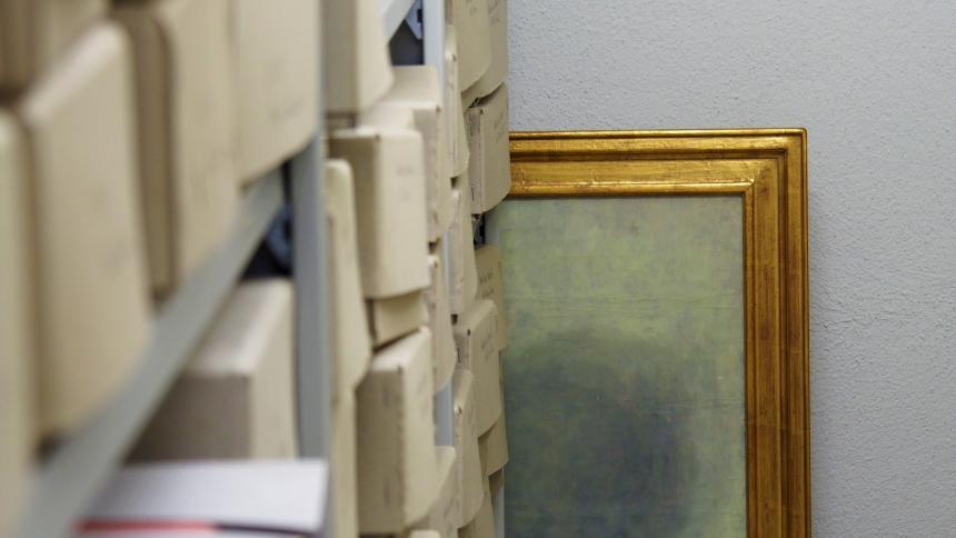 A photograph of a shelf full of boxes and a golden painting hidden behind