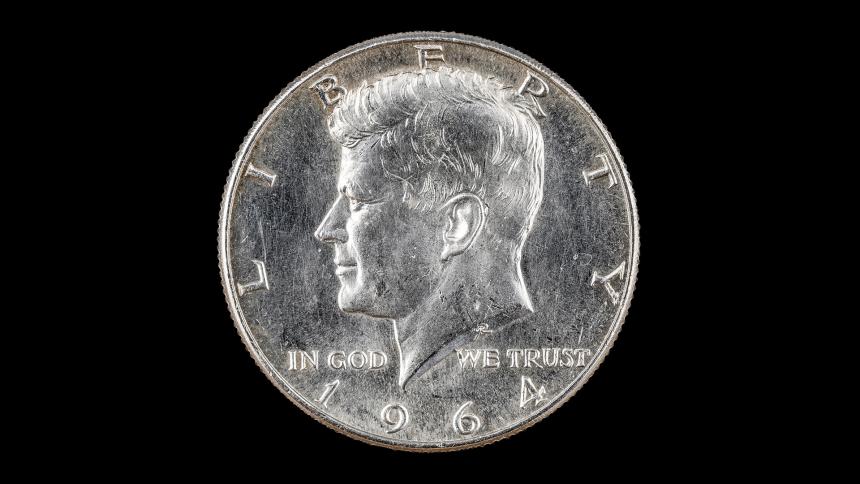 A photograph of a 1964 silver half dollar coin, showing John Fitzgerald Kennedy.