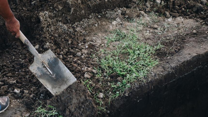 A stock photo showing an undertaker shovelling soil in a graveyard.