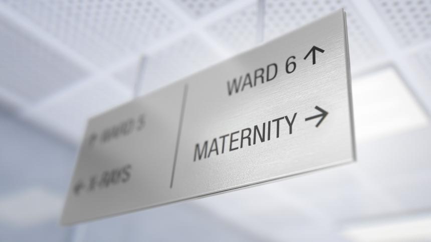 A stock photo of a hospital wayfinding sign showing directions towards a maternity ward. 