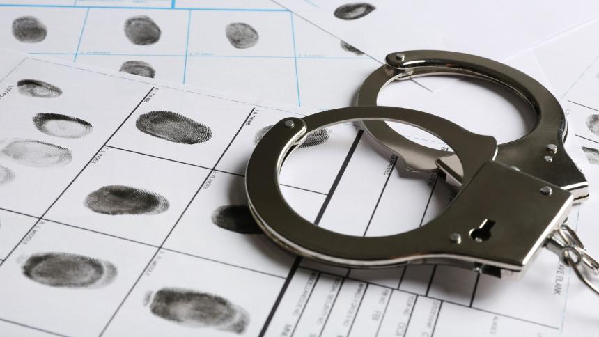 A stock photo showing police handcuffs and fingerprints
