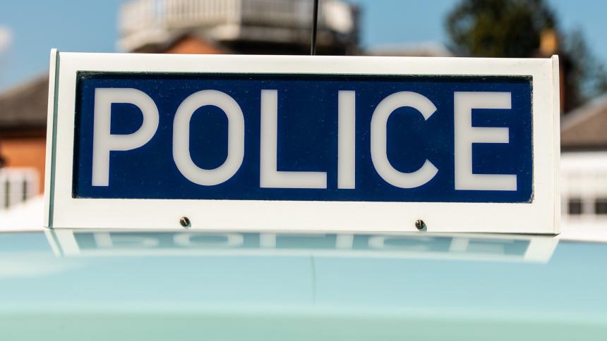 A photograph of a vintage 1970s/80s blue POLICE sign atop of a UK police car