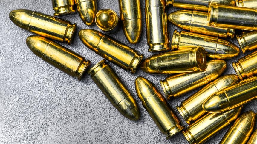 A stock photo showing bullets and ammunition on stone table.