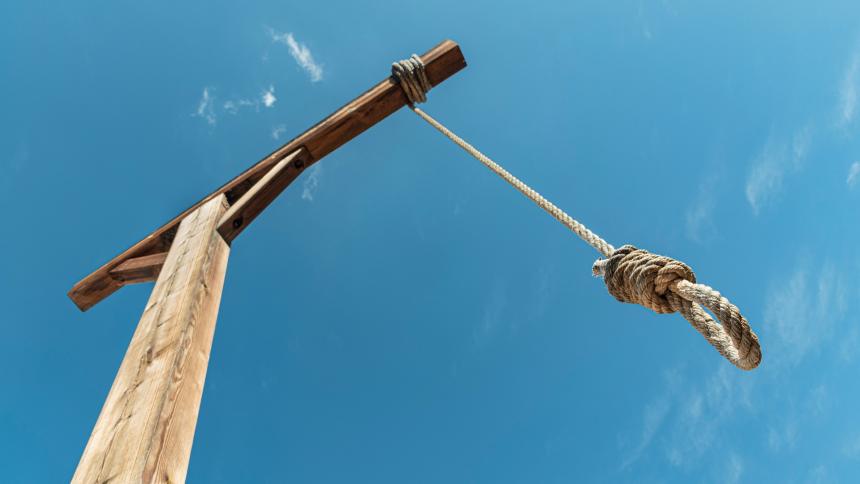 A stock photo showing gallows and a hanging rope against blue sky. 