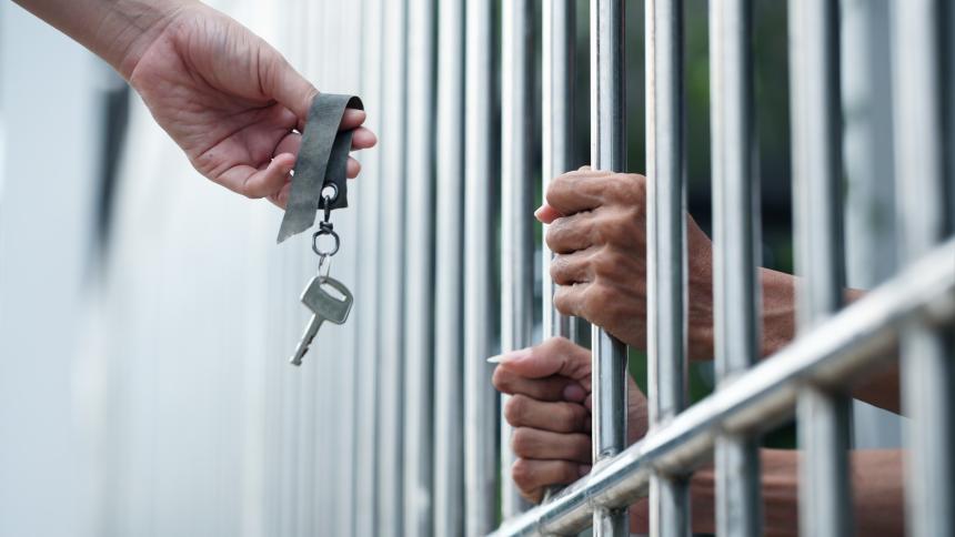 A stock photo showing a person giving a key to a prisoner.