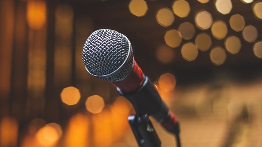 A stock photo of a microphone on stage