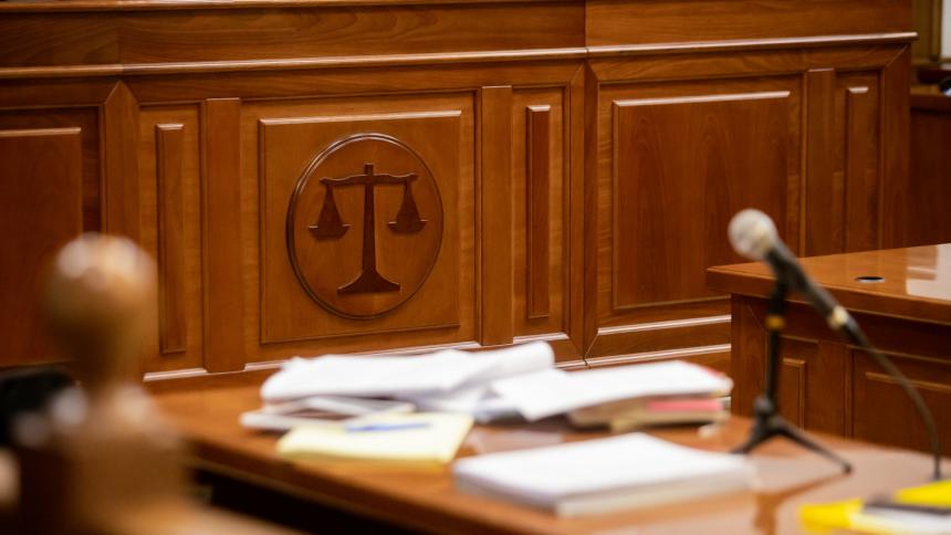A photograph of a courtroom with a wooden balance sign on the wall