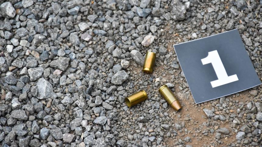 A stock photo showing a number '1' police evidence slip and 9mm pistol bullet shells on the floor.