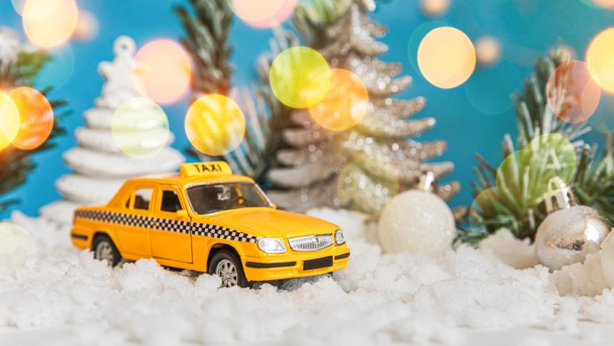A photograph of a toy taxi surrounded by Christmas trees