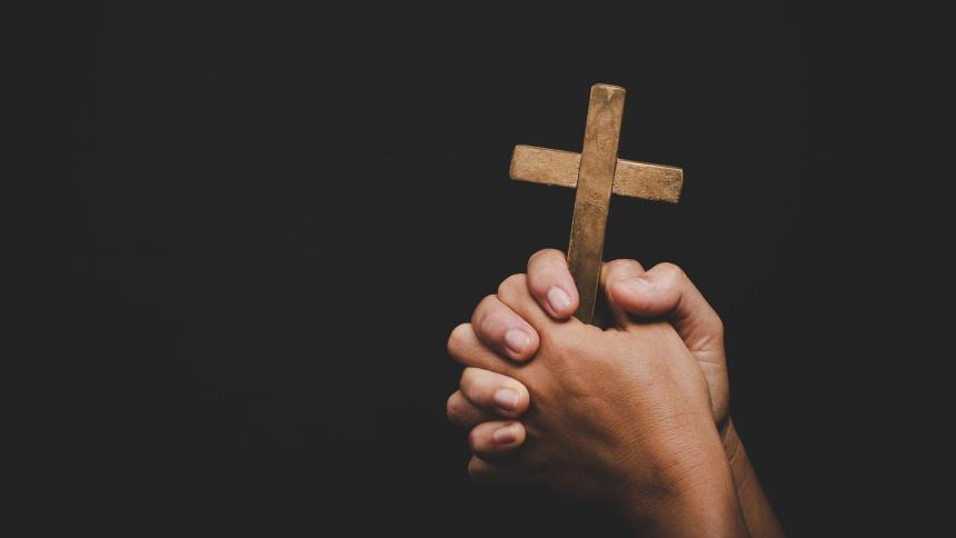 A photograph of a person holding a cross / crucifix