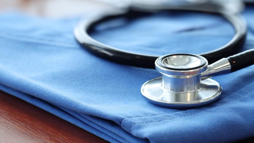 A photograph of a stethoscope with blue doctor coat