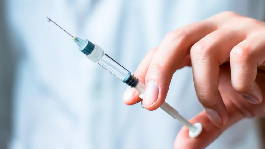 A photograph of a person holding a needle, about to administer an injection