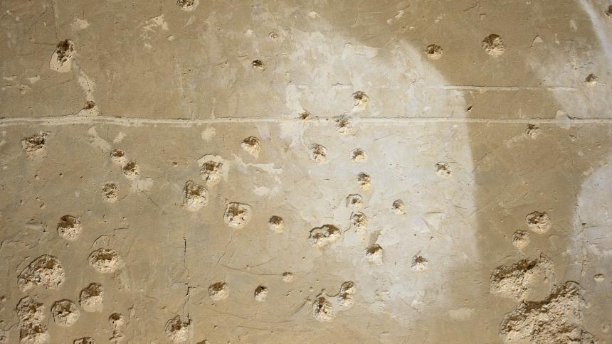 A stock photo showing bullet holes in a concrete wall
