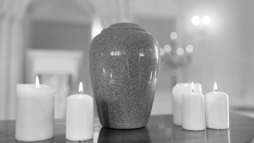 A photograph of a funerary urn and candles on a church table