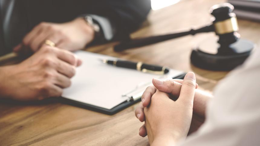 A stock photo of a courtroom gavel and a document being signed