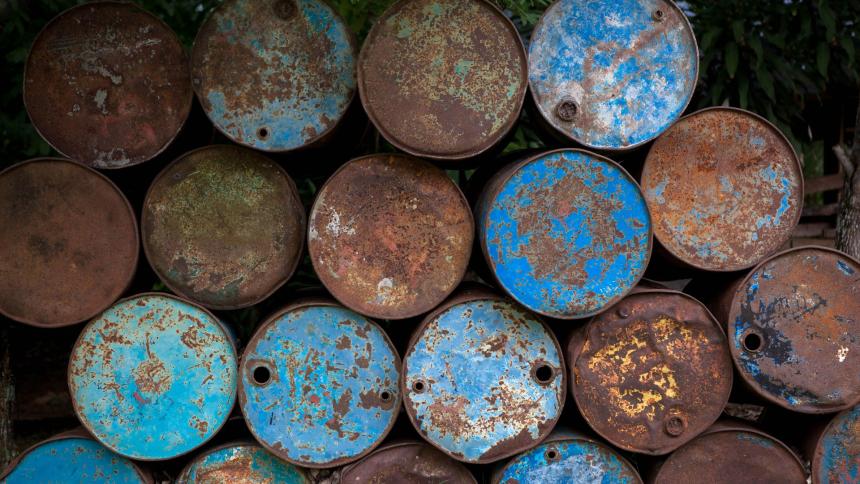 A photograph showing old rusting oil tanks and barrels