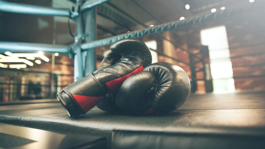 A stock photo showing a pair of boxing gloves in a boxing ring.