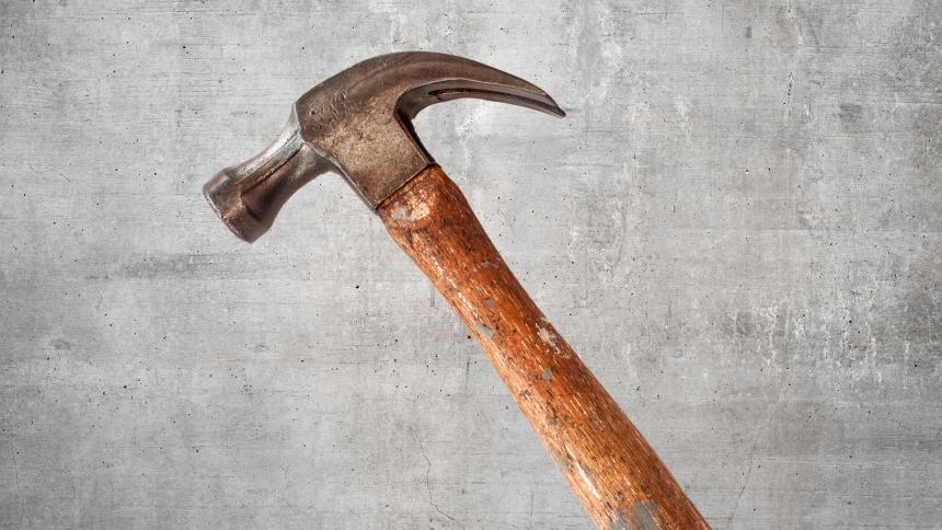A graphic photo showing a hammer against a concrete background