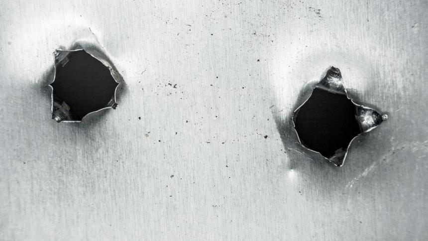 A stock image showing bullet holes in metal