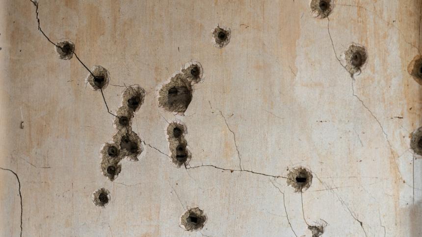 A stock photo showing bullet holes in a concrete wall