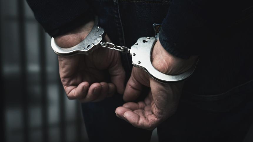 A stock photo showing someone under arrest inside a prison