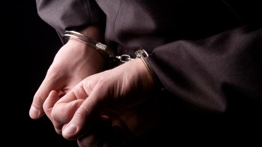 A stock photo showing a person being arrested with police handcuffs