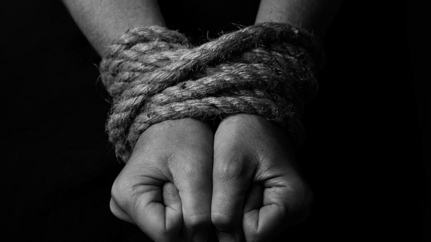 A stock image showing a person's arms tied up with rope