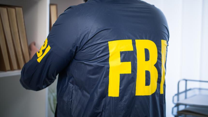 A stock image of a person wearing an FBI jacket inspecting files