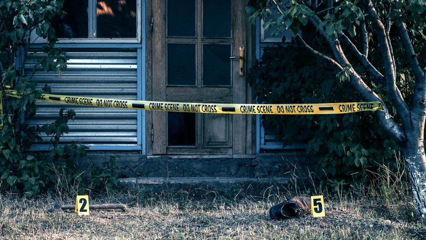 A stock image showing police tape outside of a house and a shoe on a front lawn