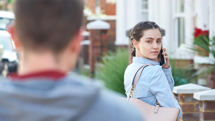 A woman looks over her shoulder as a man is following her
