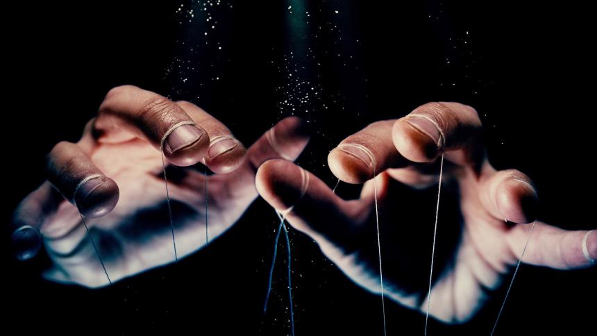 A pair of hands holding puppet strings
