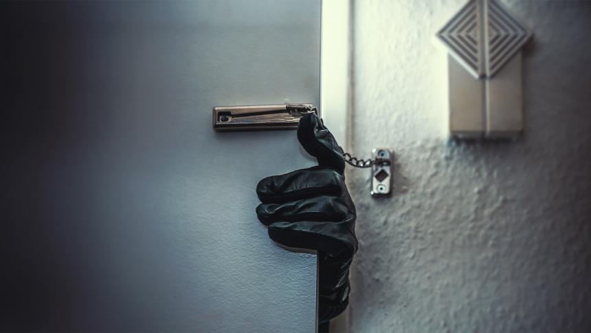 A leather-gloved hand reaching around a door