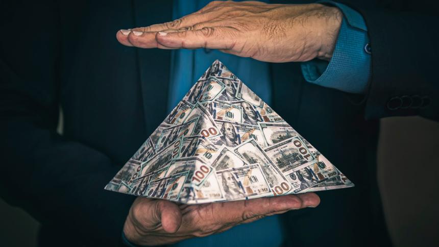 A man holding a pyramid made of US money