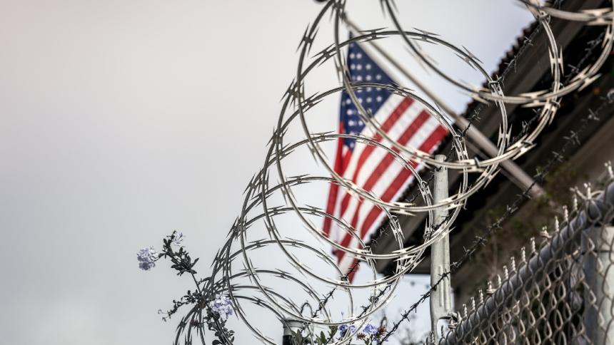 Barbed wire in front of a US flag at a prison