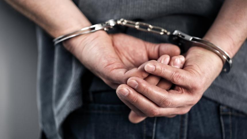 A man's hands handcuffed behind his back