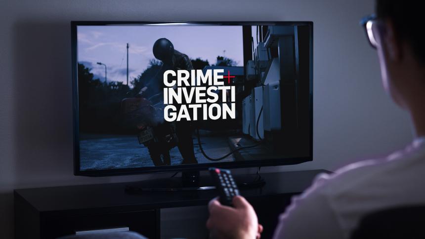 A person watching TV with Crime+Investigation on the screen