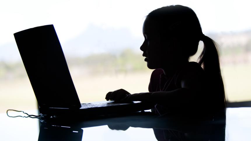 Silhouette of a young girl using a laptop computer