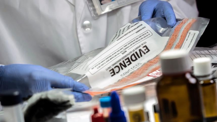 An investigator handles an evidence bag while wearing blue gloves