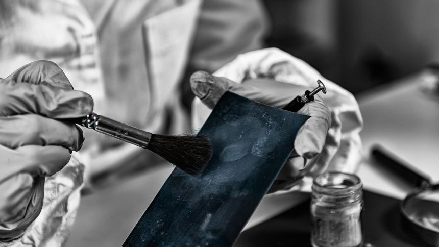A forensic expert dusting for fingerprints in a lab
