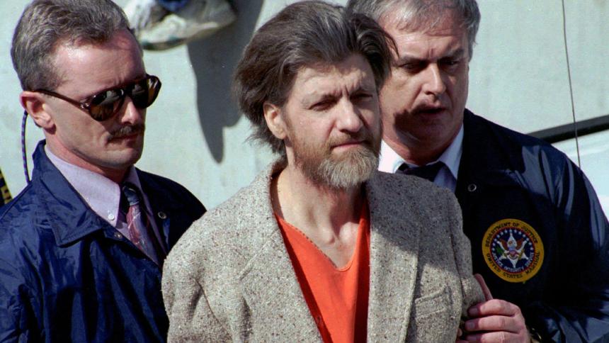 Ted Kaczynski is flanked by federal agents as he is led to a car from a federal courthouse