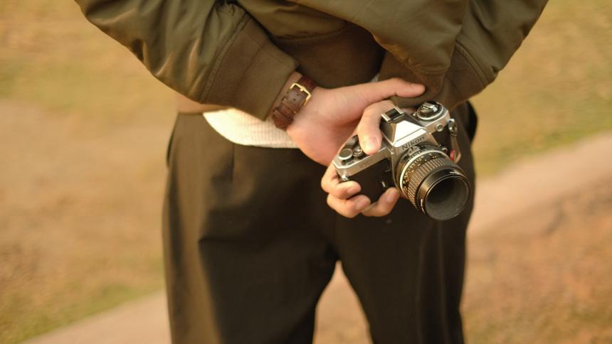 A man holding a 1980s styler camera behind his back