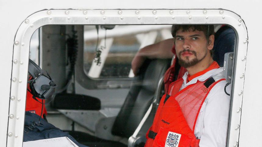 Nathan Carman looks out the window of a small boat after being rescued at sea