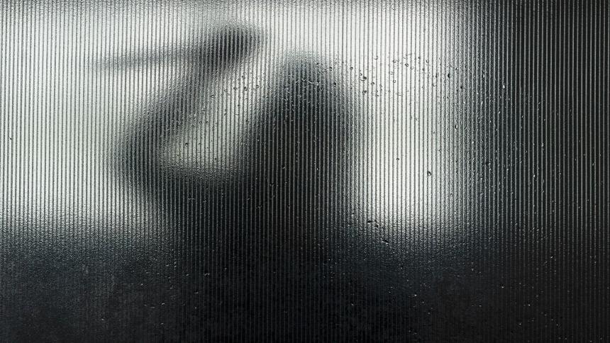Silhouette of someone wielding a knife behind frosted glass