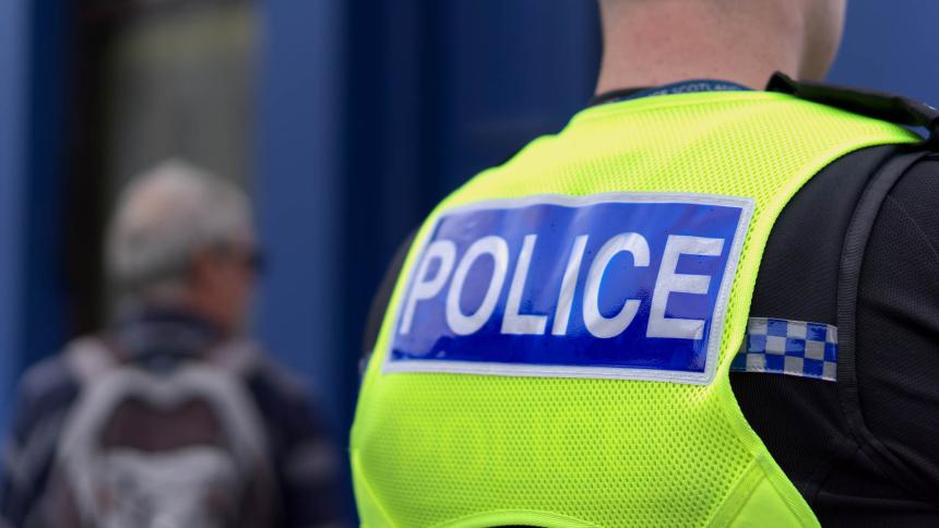 The back of a police officer wearing a reflective vest