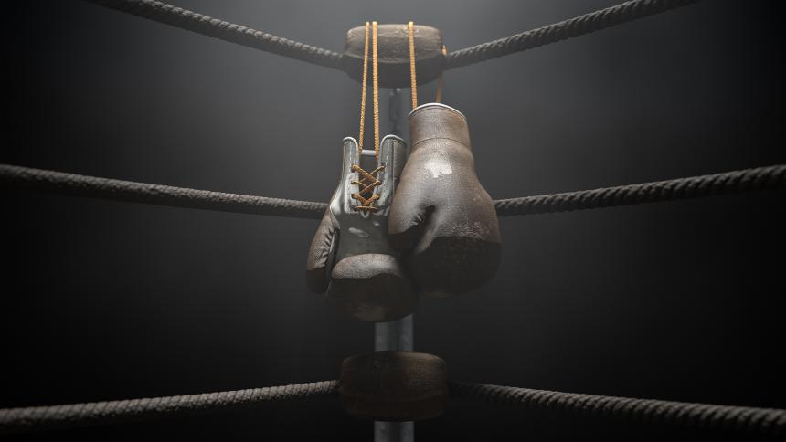 A pair of old boxing gloves hanging on the side of a boxing ring